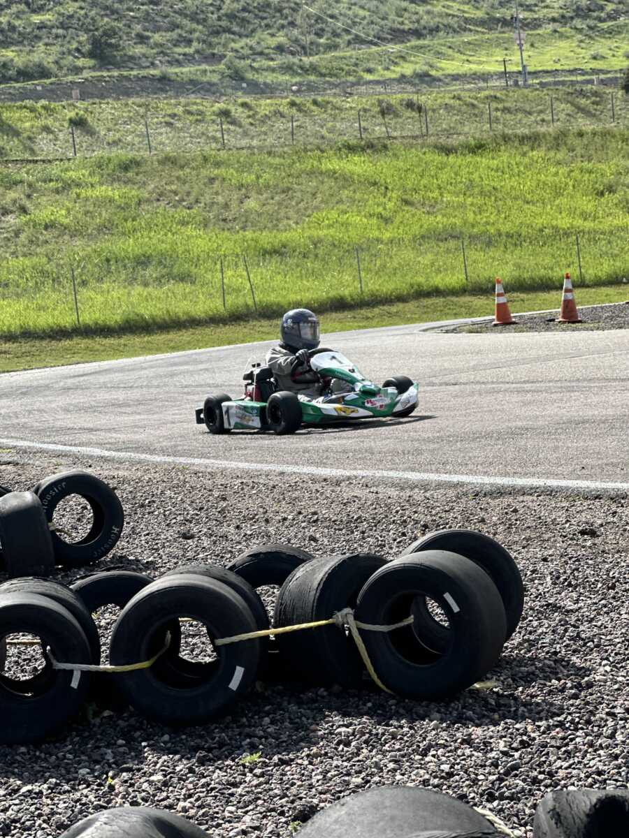 Boy racing in green go-kart on track