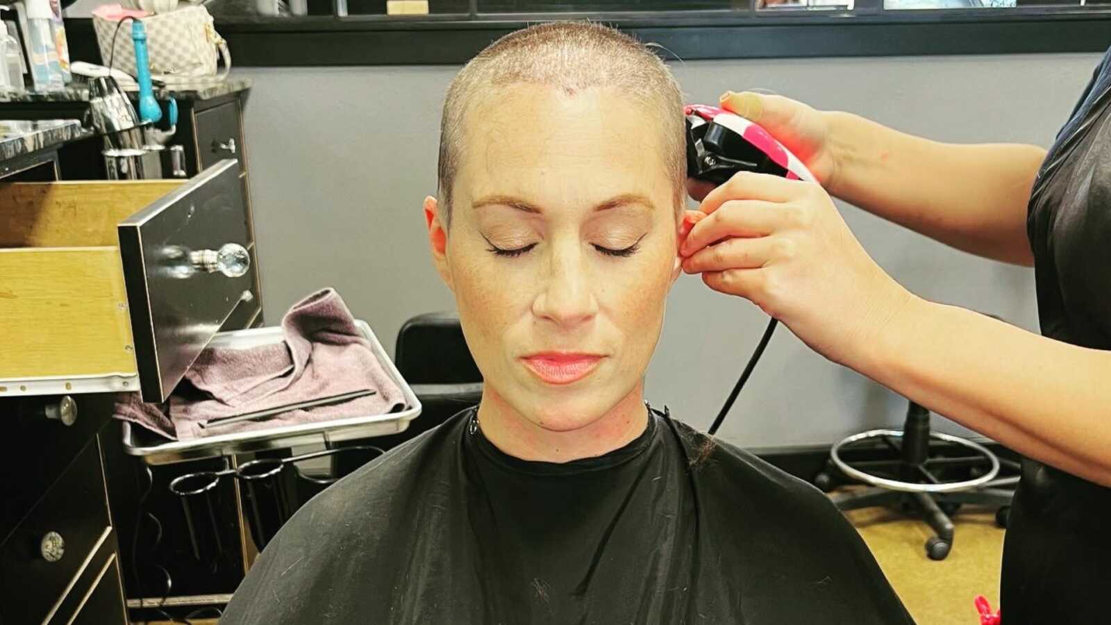 Breast cancer patient getting head shaved in hair salon