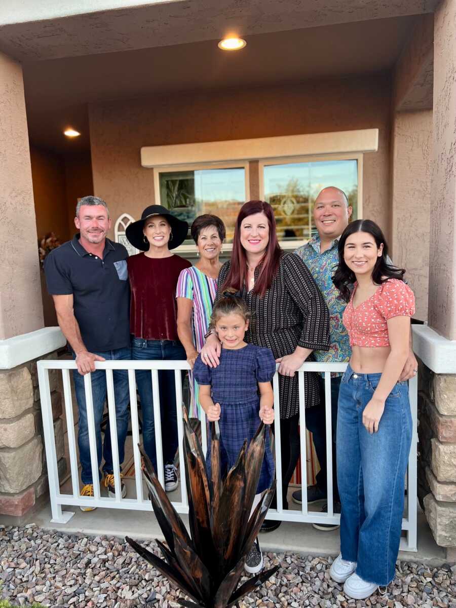 Family standing on front porch of house