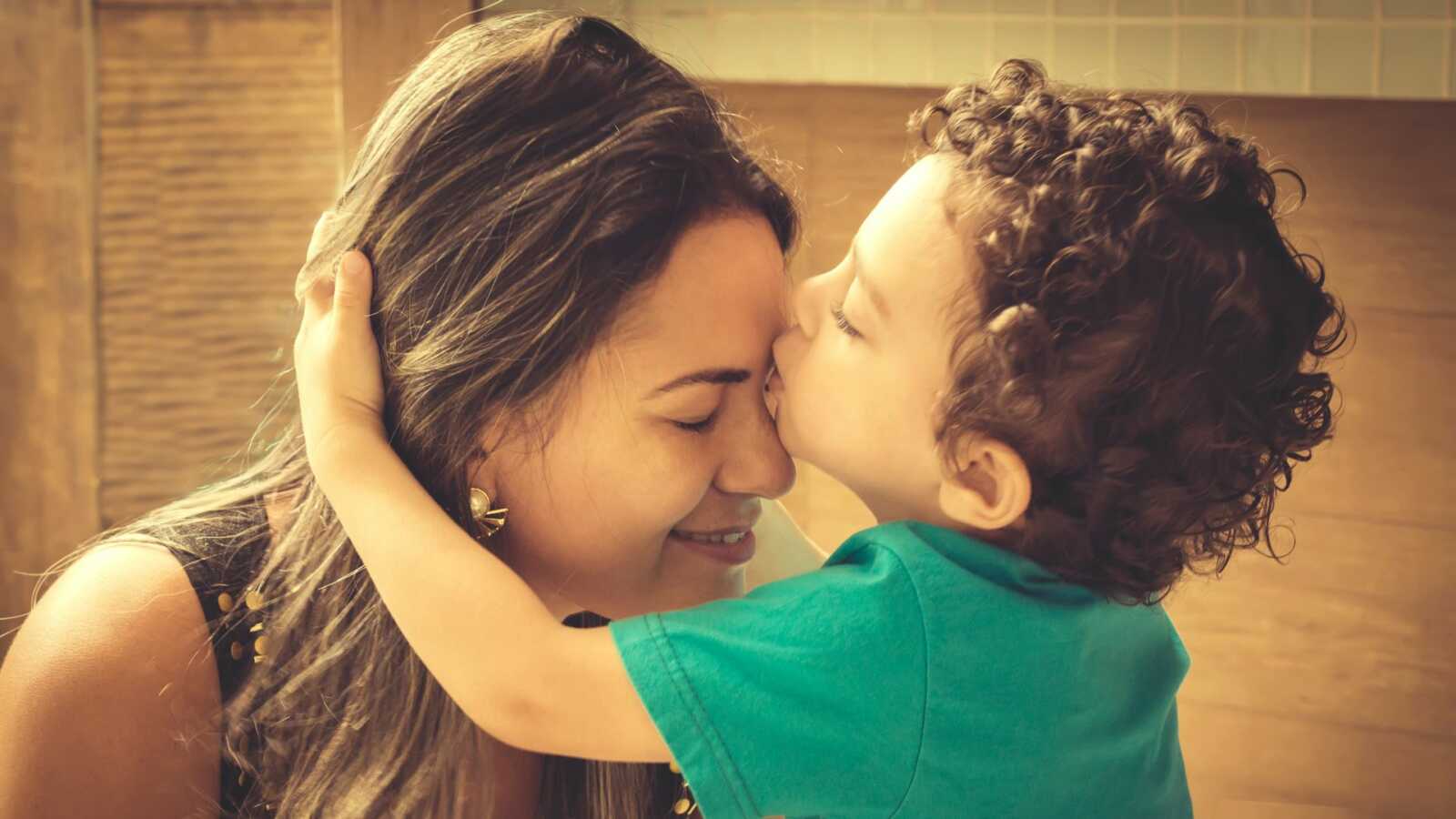 Young boy kisses his mother on the forehead