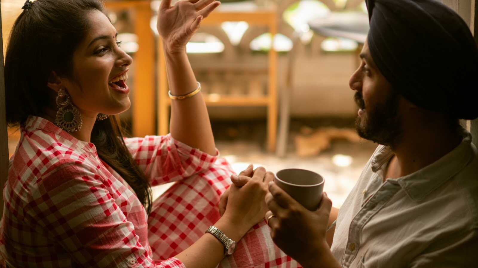 young Indian couple talking happily over coffee