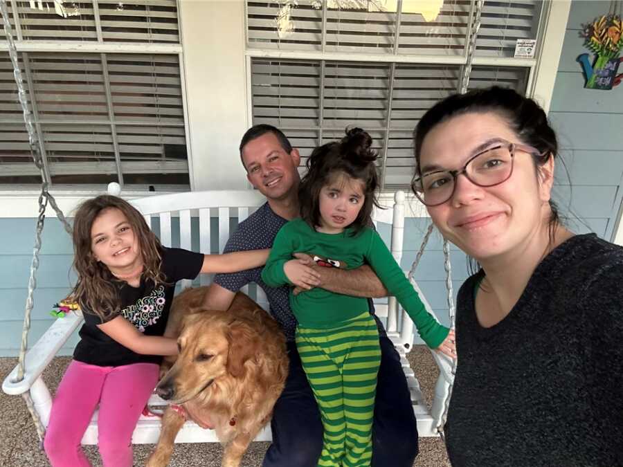 Family sits outside on a porch swing