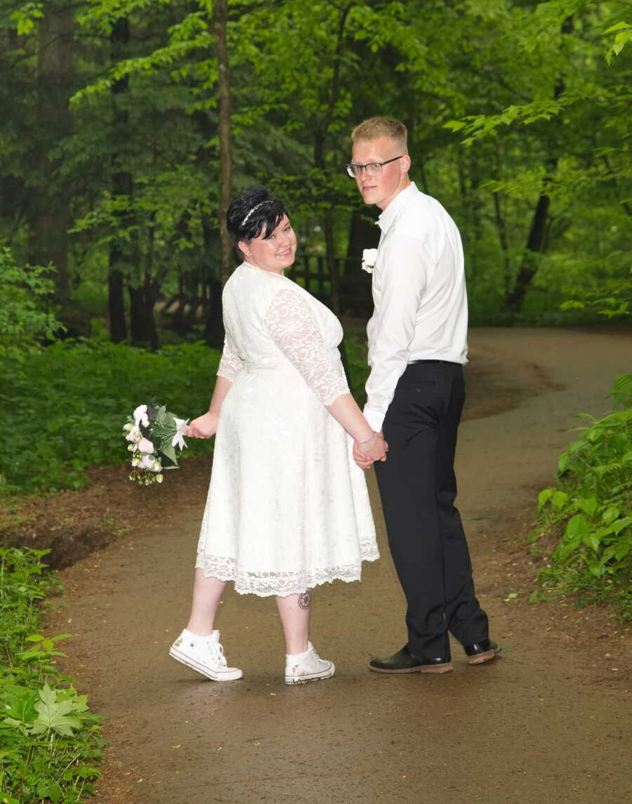 Bride and groom hold hands on trail