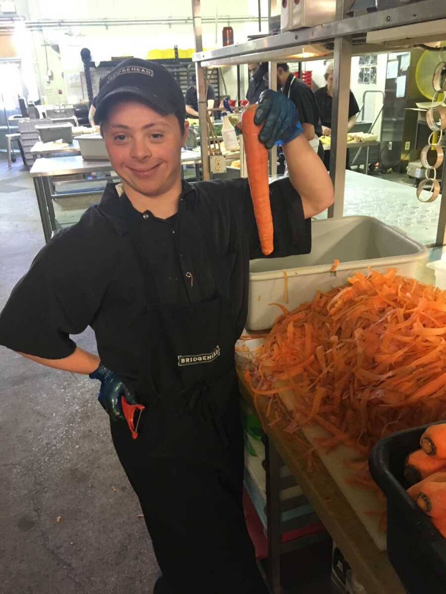 Teen with Down syndrome cutting carrots in kitchen