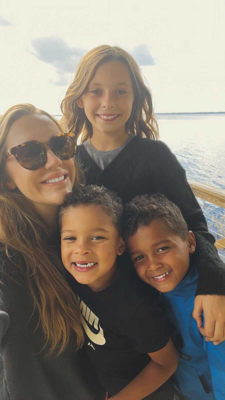 Foster mom smiling next to three kids