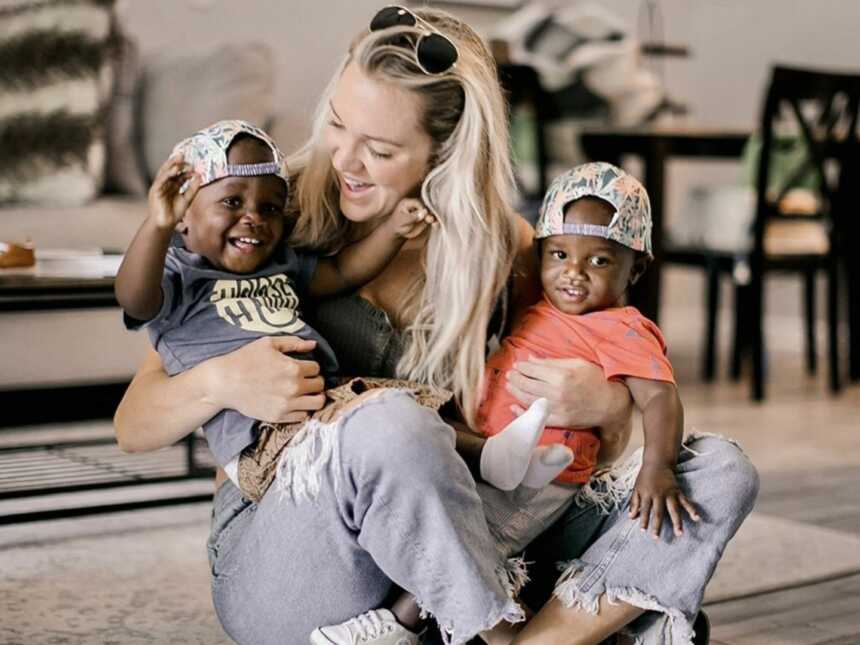 Single foster mom holding smiling twins in lap