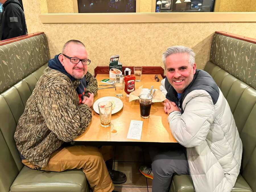Man sitting with homeless man at diner