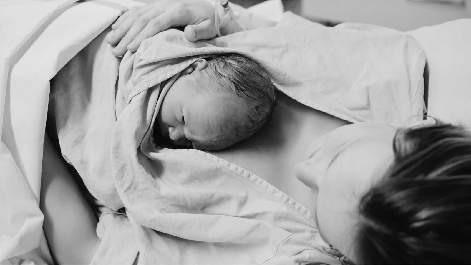 Postpartum mom holding newborn baby in hospital bed