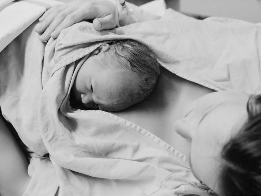 Postpartum mom holding newborn baby in hospital bed