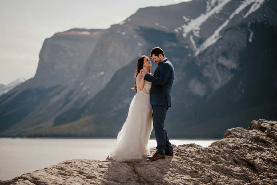 Bride and groom dancing beside mountain and lake
