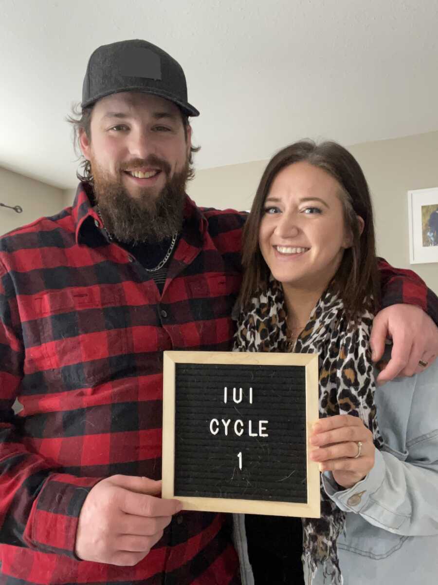 Husband and wife holding up IUI announcement sign