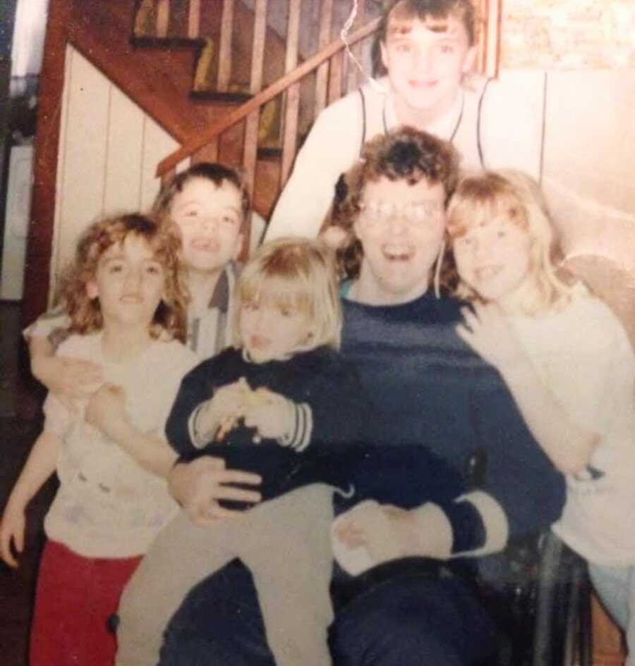 Mom smiling in front of staircase next to her four children