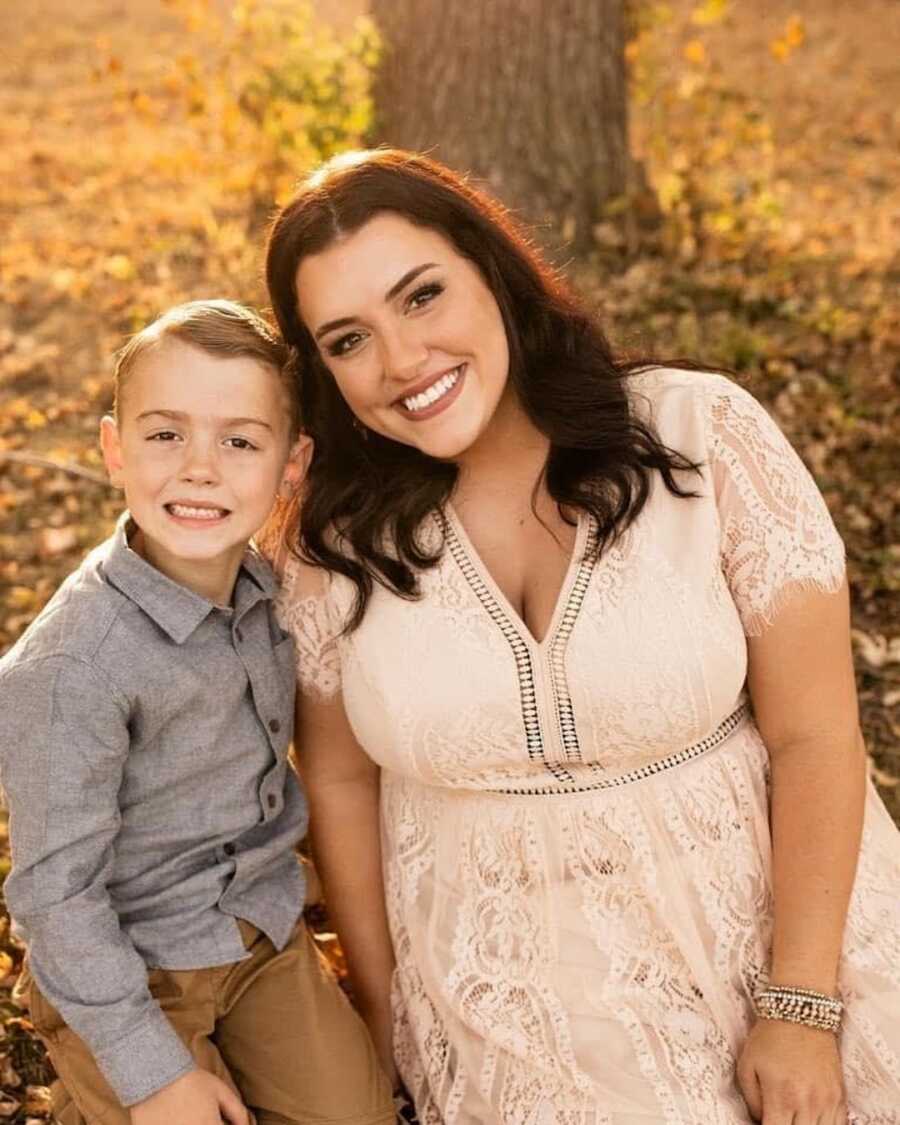 Mom and son smiling in front of tree trunk