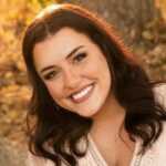 Woman smiling in front of tree trunk