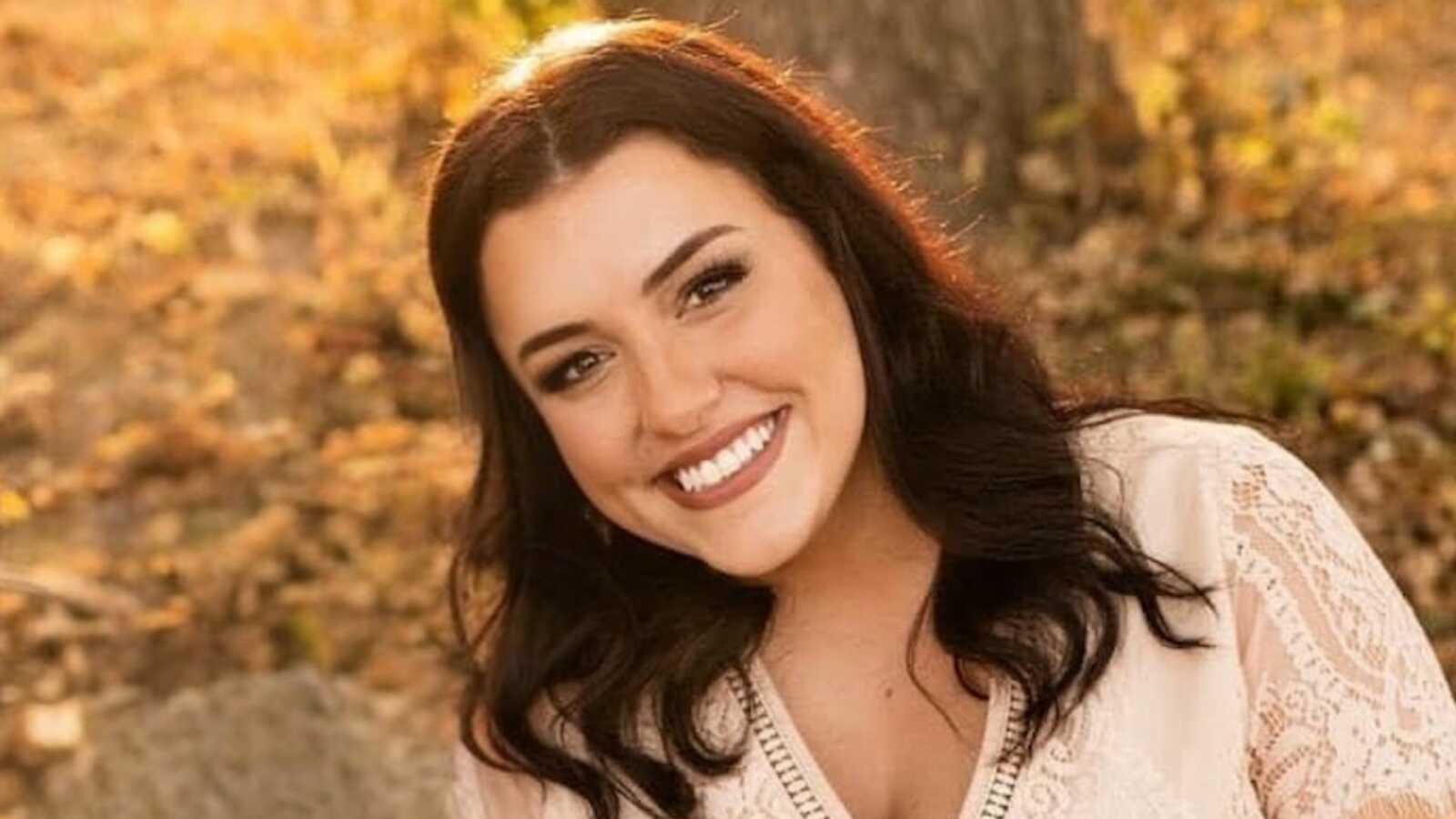 Woman smiling in front of tree trunk