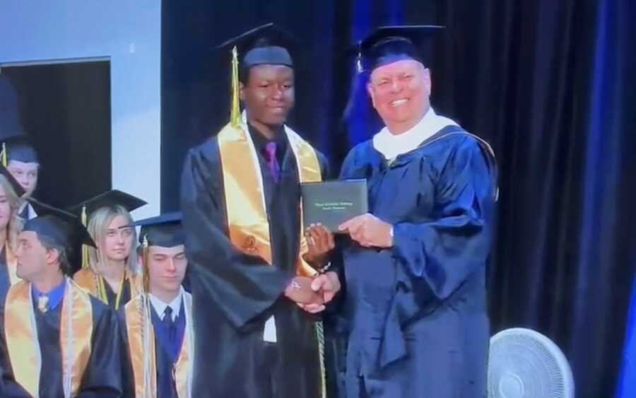 Young man receiving high school diploma