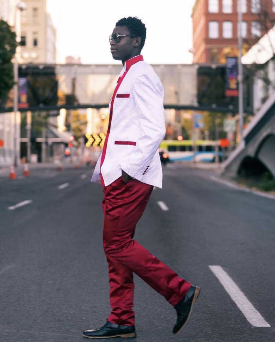 Young man walking down street in red silk suit